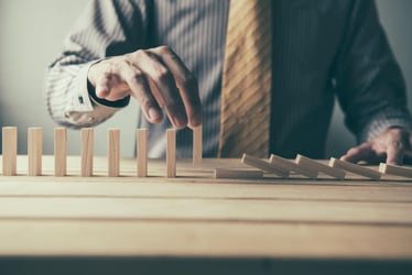 Man placing dominoes as a metaphor for intricate growth.