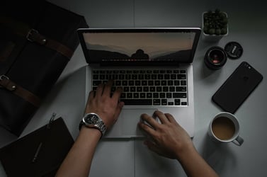 person sits at laptop with coffee and other comforts