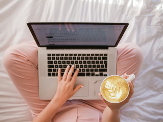 Person sitting cross legged with coffee and laptop