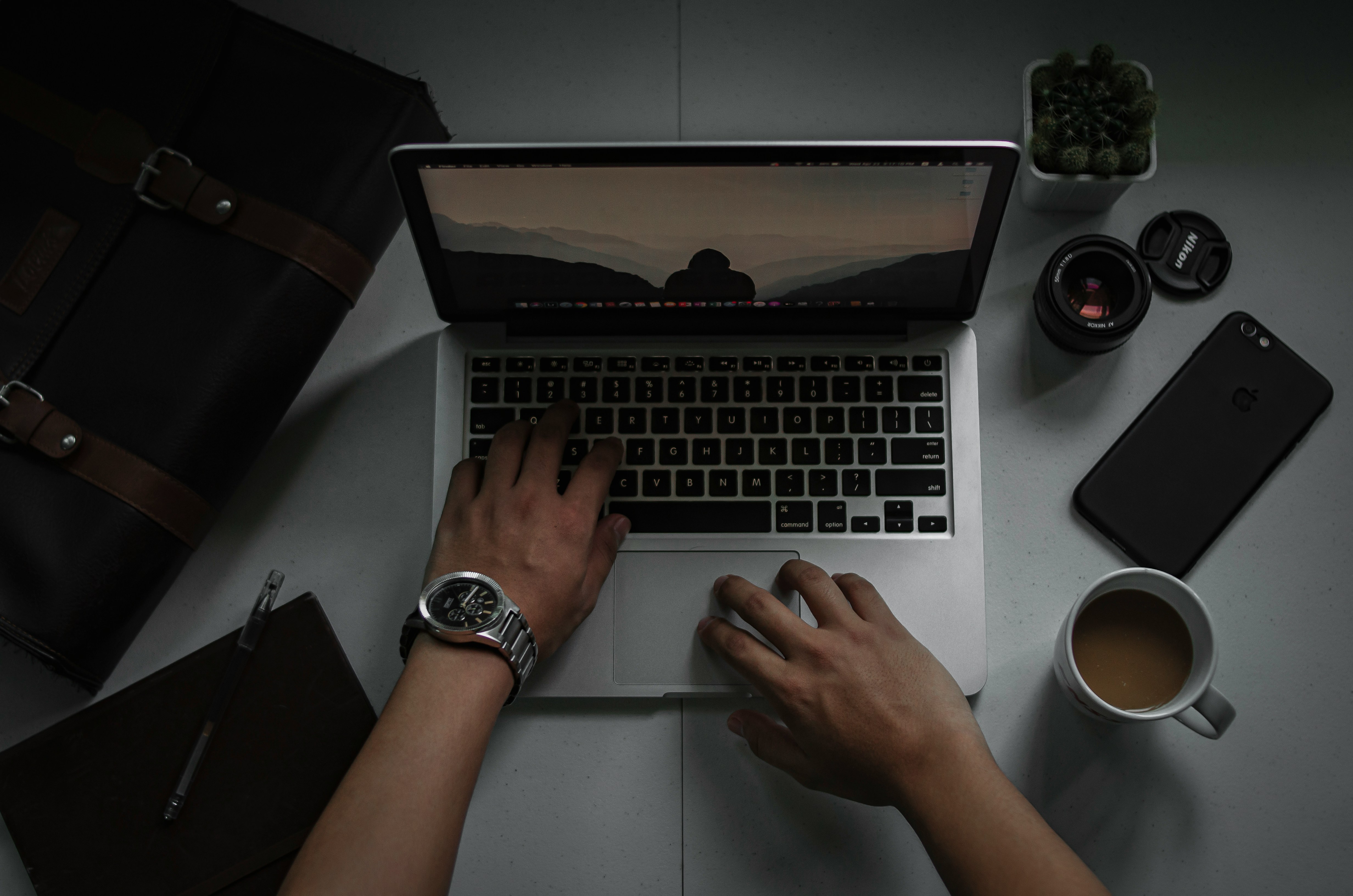 person sits at laptop with coffee and other comforts